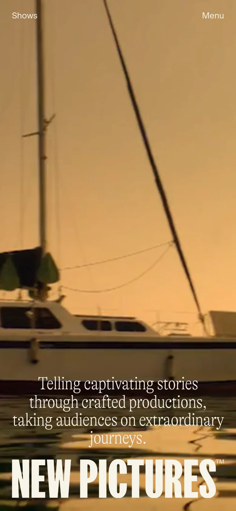 The mobile version displays a full-screen hero image of a sailboat at sunset with the 'NEW PICTURES' logo and mission statement centered. The layout is simplified with 'Shows' and 'Menu' links positioned at the top corners of the screen for easy navigation.