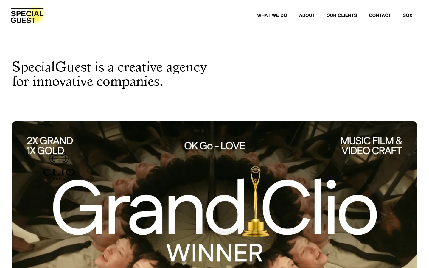 The desktop homepage features a minimalist white background with black serif typography. A large hero image displays a 'Grand Clio Winner' award graphic over a montage of faces, accompanied by text reading '2X GRAND 1X GOLD' and 'MUSIC FILM & VIDEO CRAFT'. A navigation menu is located at the top right with links for What We Do, About, Our Clients, Contact, and SGX.