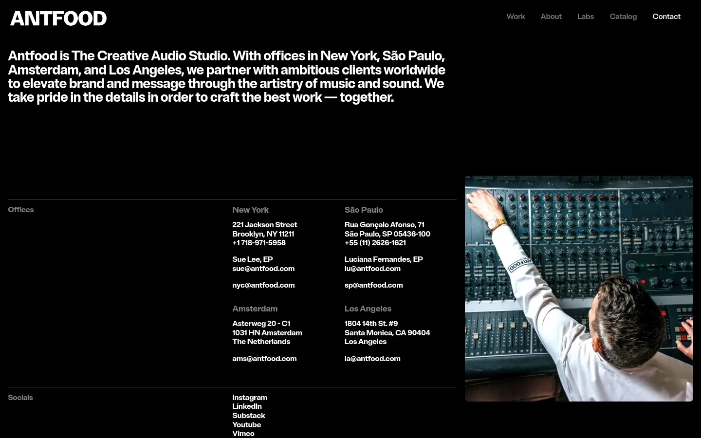 The desktop contact page features a dark theme with white text and a large hero section containing a mission statement. The layout uses a multi-column grid to list office locations in New York, São Paulo, Amsterdam, and Los Angeles, alongside social media links. A large photograph of a person working at a professional audio mixing console is positioned on the right side of the screen.
