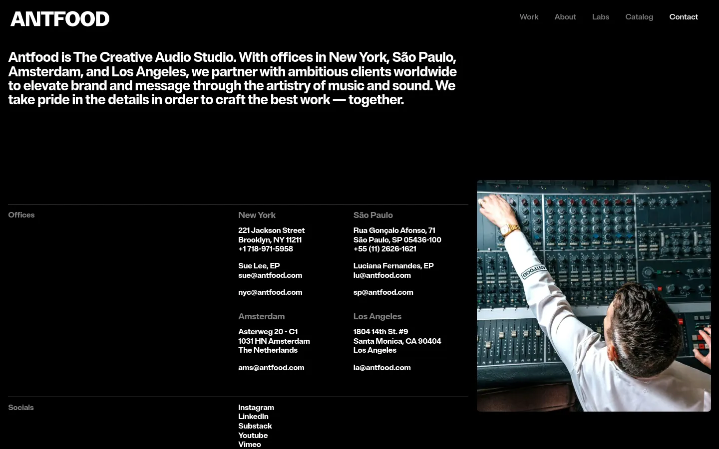The desktop contact page features a dark theme with white text and a large hero section containing a mission statement. The layout uses a multi-column grid to list office locations in New York, São Paulo, Amsterdam, and Los Angeles, alongside social media links. A large photograph of a person working at a professional audio mixing console is positioned on the right side of the screen.