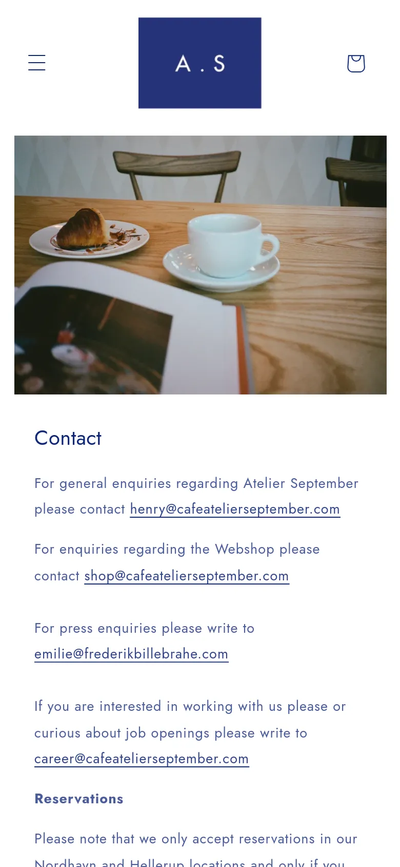 The mobile version presents a vertically stacked layout with a simplified header containing a hamburger menu, the 'A.S' logo, and a shopping bag icon. The hero image of the coffee and croissant is scaled down to fit the width, followed by the 'Contact' heading and contact information text. The overall aesthetic remains clean and white with high-contrast black text.