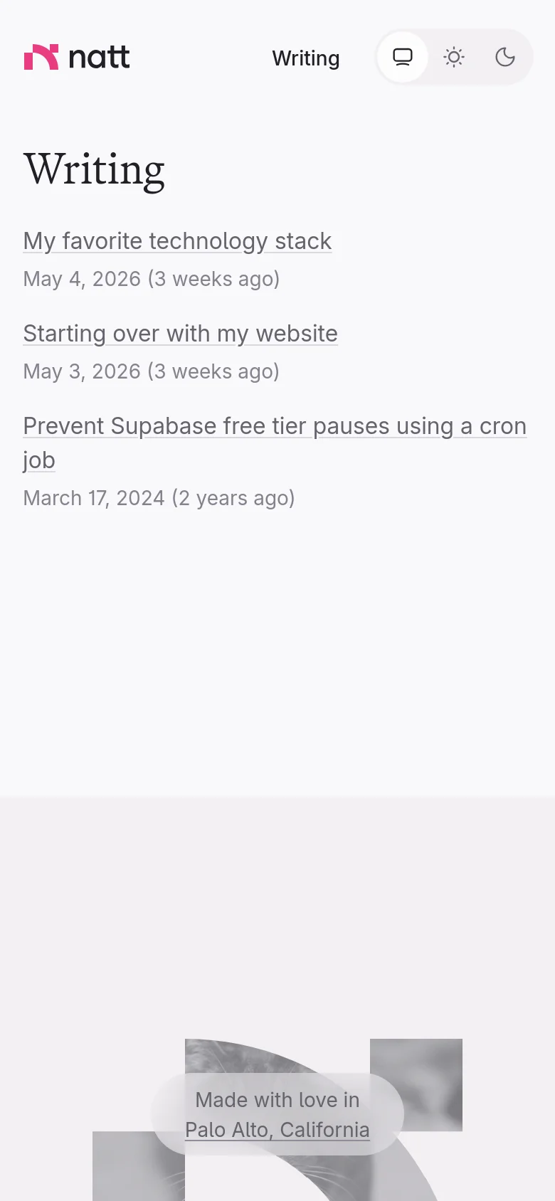The mobile version maintains the minimalist aesthetic but shifts to a single-column layout. The header is condensed, and the list of writing articles spans the width of the screen for easier scrolling. The footer features the same grayscale cat imagery and location text, centered at the bottom.