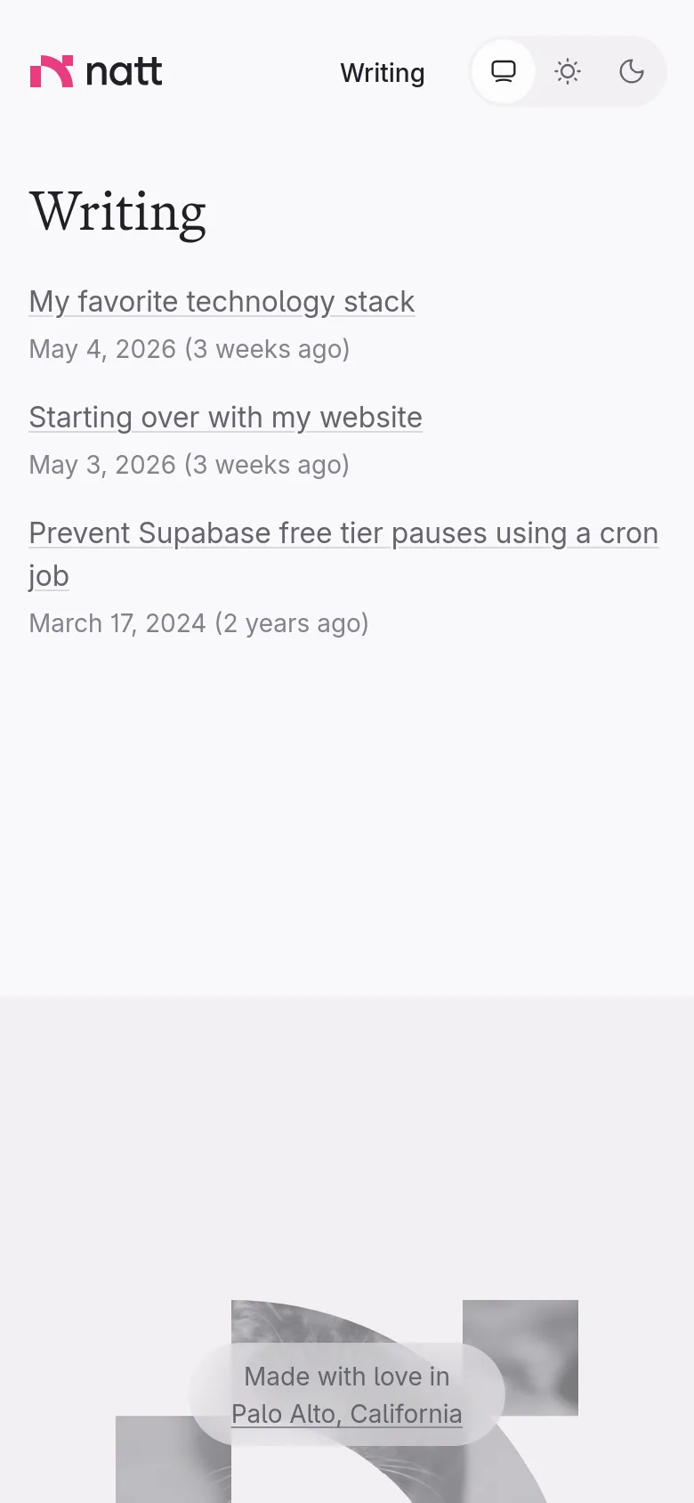 The mobile version maintains the minimalist aesthetic but shifts to a single-column layout. The header is condensed, and the list of writing articles spans the width of the screen for easier scrolling. The footer features the same grayscale cat imagery and location text, centered at the bottom.