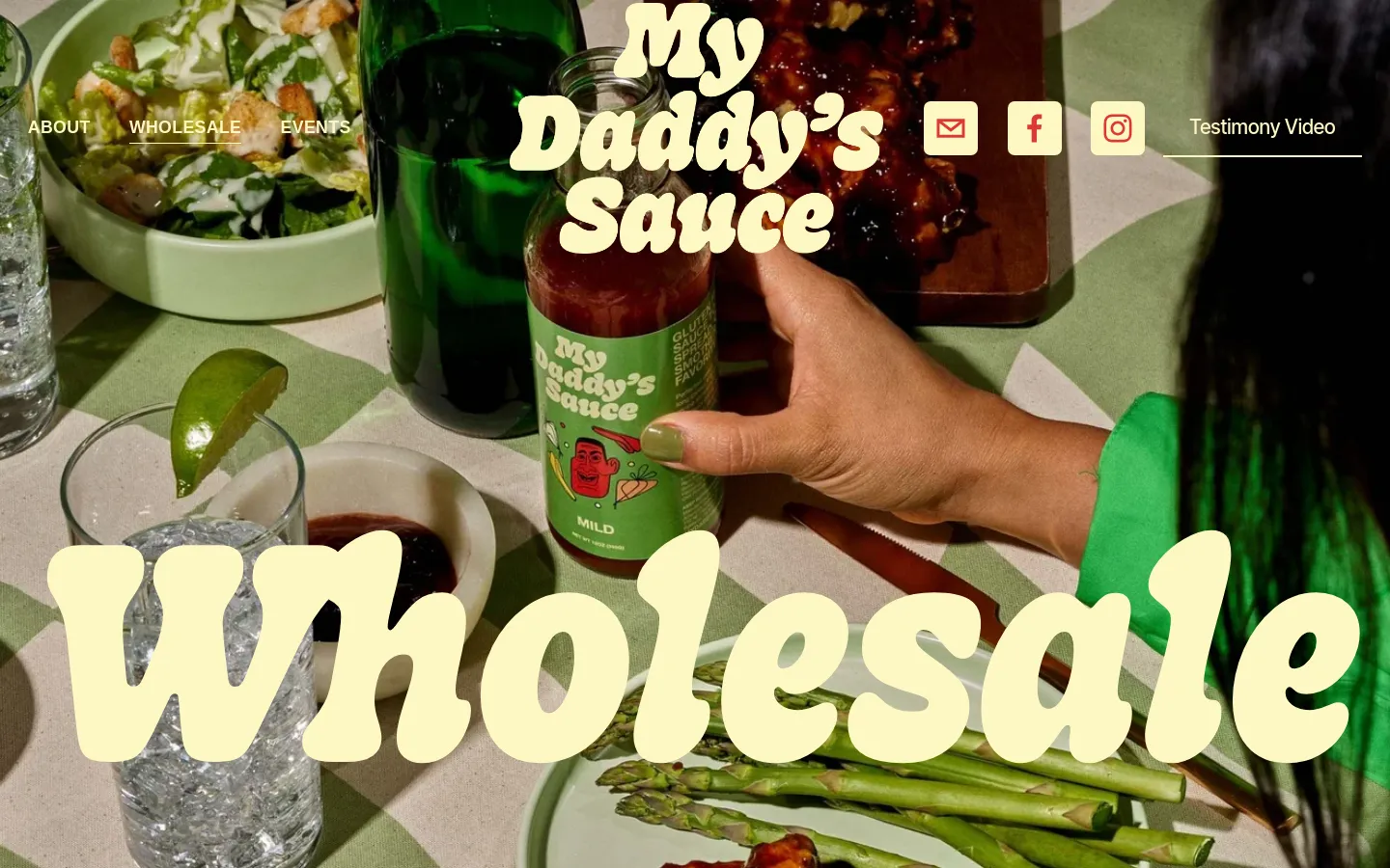 The desktop page features a large hero image of a person holding a bottle of My Daddy's Sauce at a dining table with food and drinks. A large cream-colored 'Wholesale' headline is overlaid on the image, and a navigation bar with links like 'About' and 'Wholesale' sits at the top. Below the hero section, there is text inviting wholesale inquiries and a link to Made in Milwaukie for retail sales.