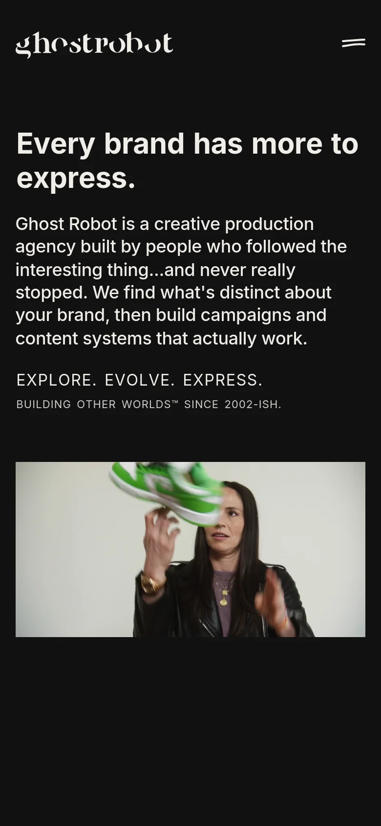 The mobile version uses a simplified dark layout with a large white logo and a hamburger menu icon at the top. The main headline and text are stacked vertically, followed by a video hero image showing a person with a green object, replacing the wide cinematic video seen on desktop.