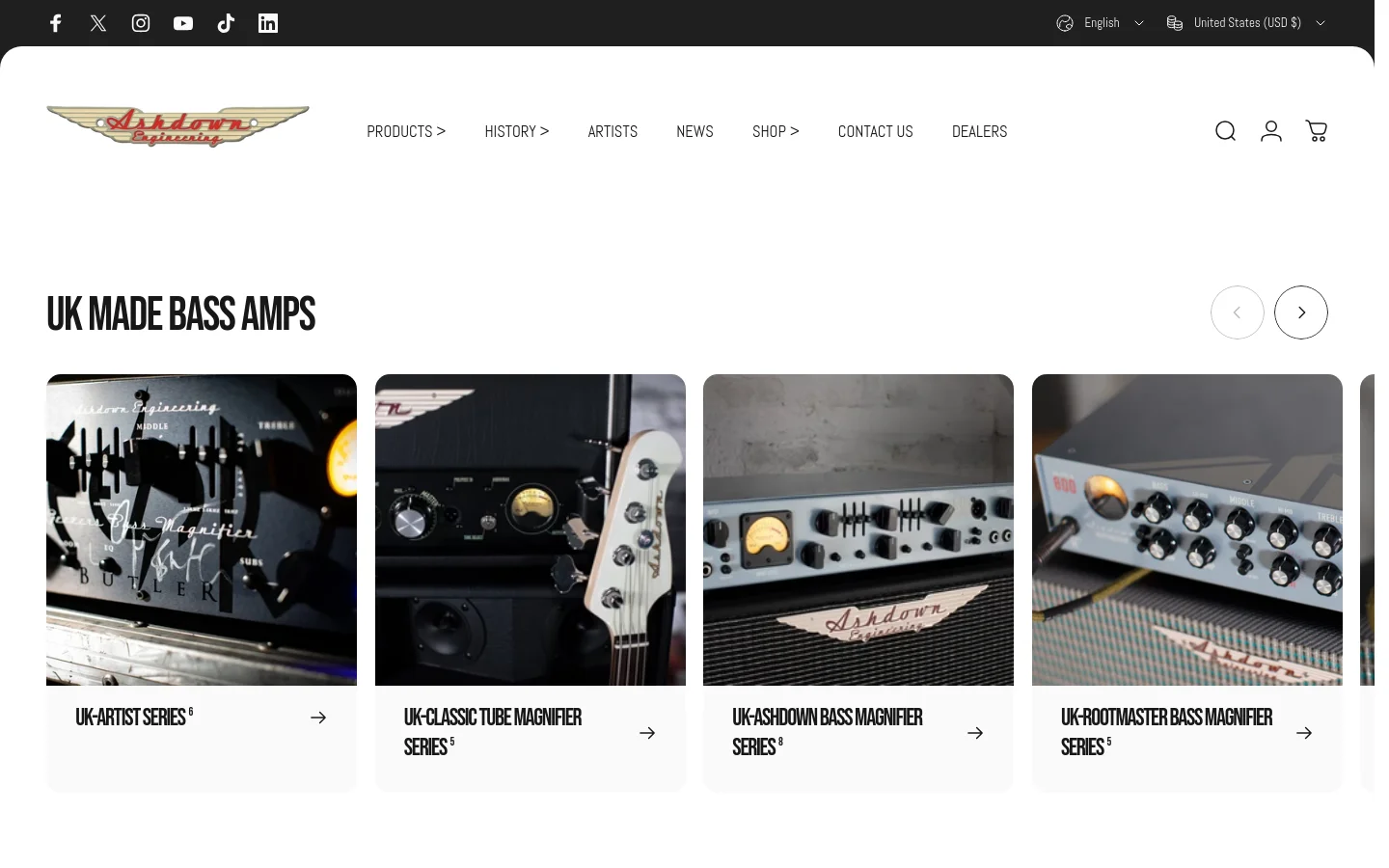 The Ashdown Engineering homepage features a clean white layout with a top navigation bar containing the brand logo, product categories, and utility icons. A large hero section displays a video preview, followed by a 'UK MADE BASS AMPS' section with a horizontal carousel of large product image cards. Each card features high-quality photography of amplifiers and includes a series title and a directional arrow link.
