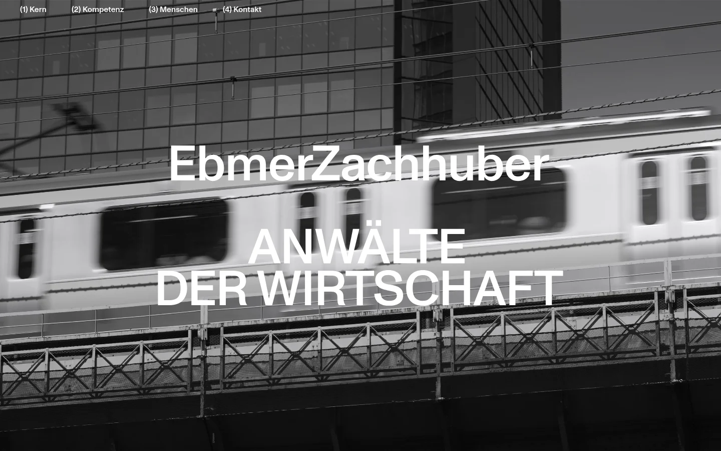 EbmerZachhuber homepage featuring a full-bleed grayscale hero image of a moving train against a modern glass building. Large white sans-serif typography reads EbmerZachhuber ANWÄLTE DER WIRTSCHAFT, set against a minimalist monochrome design with a simple top navigation menu.