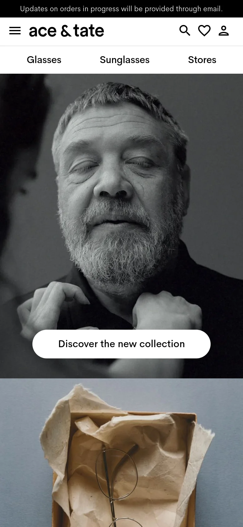 The mobile version displays a vertical black and white hero image of a man's face, with the 'Discover the new collection' button positioned centrally over the image. The navigation is condensed into a hamburger menu on the left, with the brand logo centered and search, favorites, and profile icons on the right. The top announcement bar remains visible above the header.