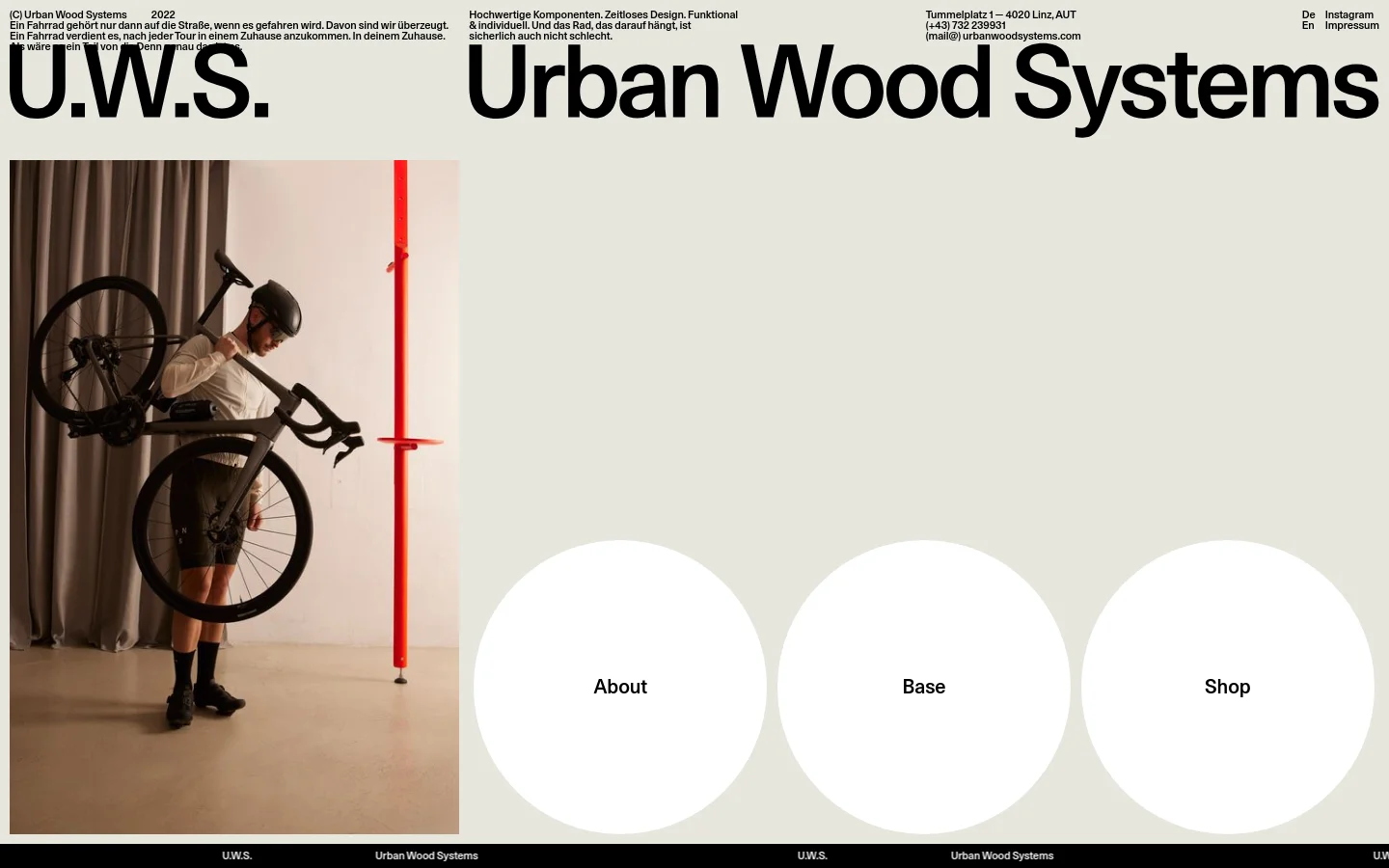The desktop homepage features a large headline 'U.W.S. Urban Wood Systems' next to a hero image of a person carrying a bicycle near a red vertical bike stand. Below the hero section, three large white circular buttons labeled 'About', 'Base', and 'Shop' are arranged horizontally against a light grey background.