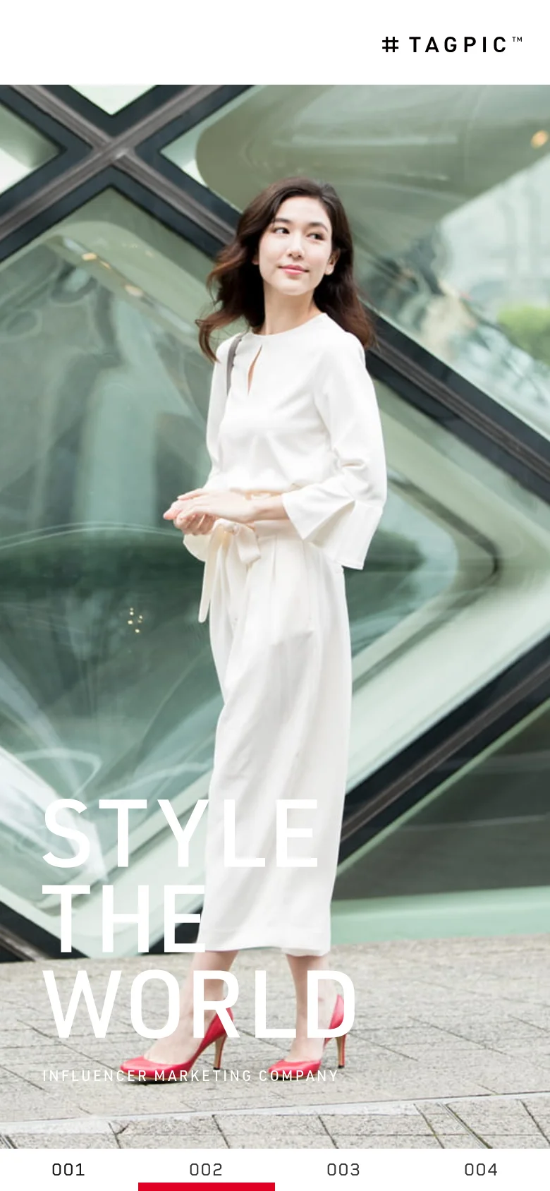 The mobile version presents a full-width vertical hero image of the woman in a white dress, with the 'STYLE THE WORLD' text overlaid in large white letters at the bottom. The layout is simplified for vertical scrolling, and a numbered pagination bar (001 to 004) is located at the very bottom of the screen.