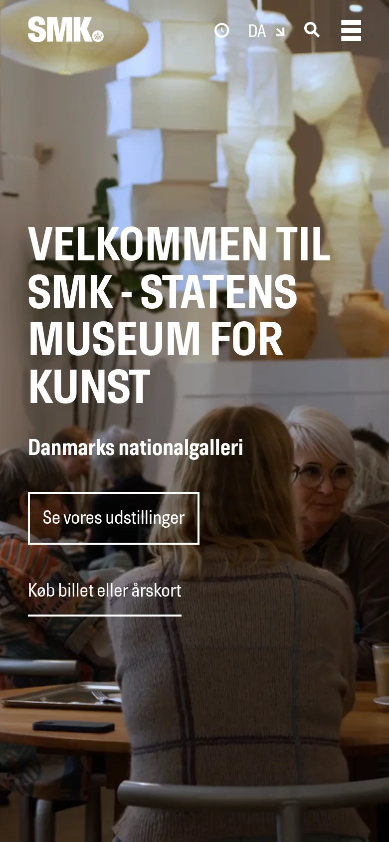 The mobile version uses a full-screen vertical hero image showing people sitting in a cafe or gallery space. The navigation is condensed into a hamburger menu and a top bar containing the logo, opening hours, language selector, and search icon. The main headline and calls to action are centered and stacked vertically over the image.