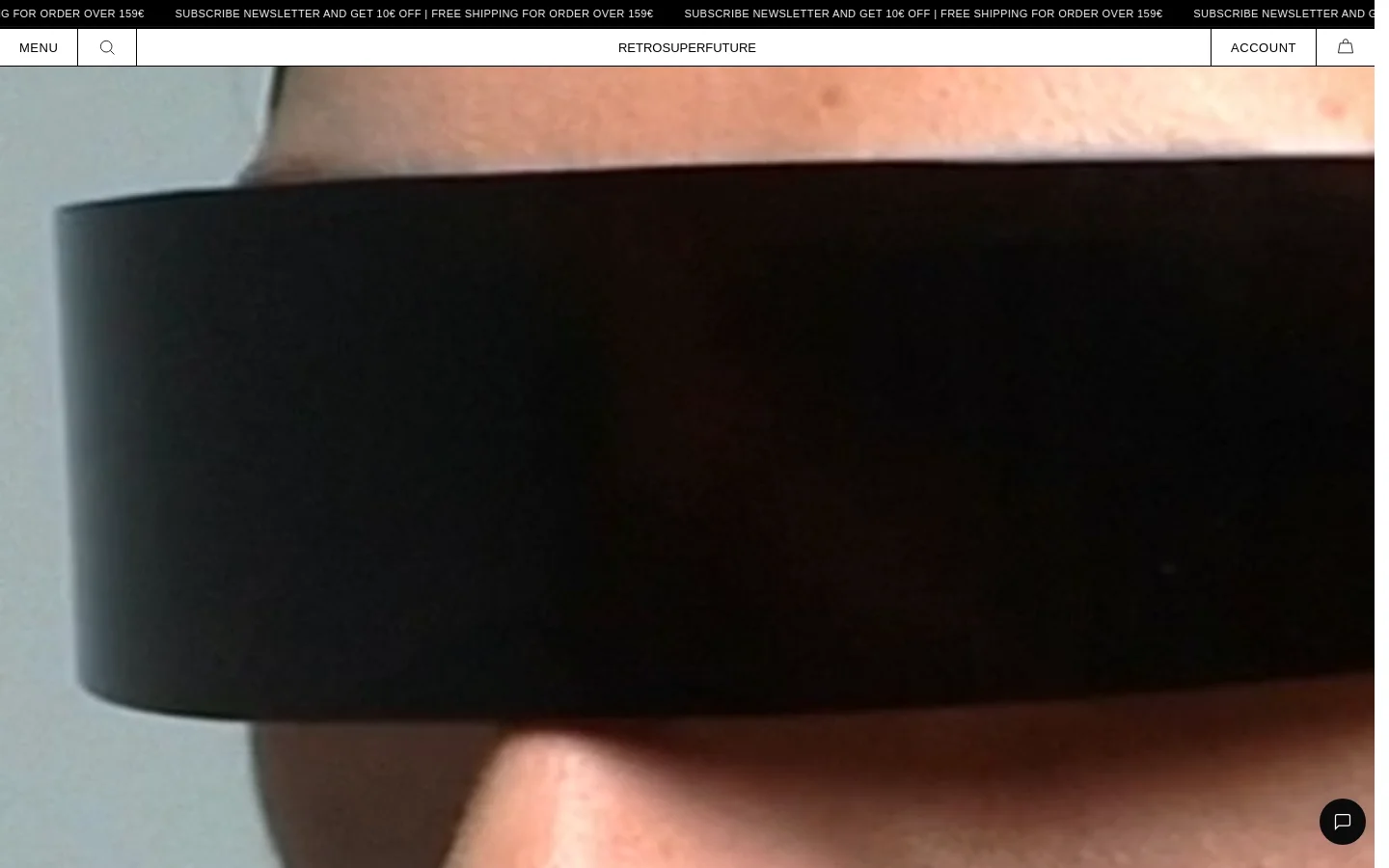 The desktop homepage features a minimalist white header with a menu, search icon, brand logo, account link, and shopping bag. A large hero image shows a close-up profile of a person wearing thick black eyewear, followed by a product grid displaying various eyewear styles with names and prices.