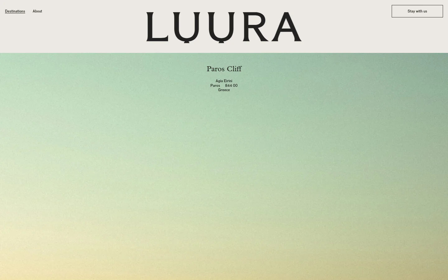 The desktop webpage features a minimalist design with a large 'LUURA' logo at the top center and a 'Stay with us' button on the right. The hero section displays the headline 'Paros Cliff' followed by the address over a soft green and yellow gradient background that transitions into a sea view at the bottom.