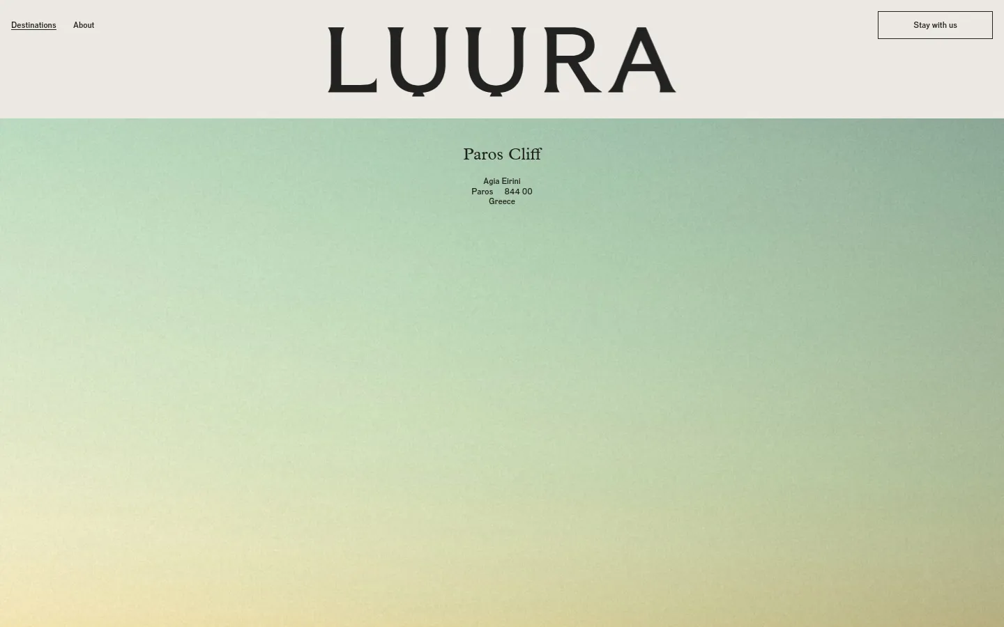 The desktop webpage features a minimalist design with a large 'LUURA' logo at the top center and a 'Stay with us' button on the right. The hero section displays the headline 'Paros Cliff' followed by the address over a soft green and yellow gradient background that transitions into a sea view at the bottom.