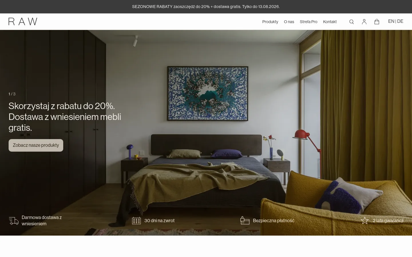 The desktop homepage features a minimalist design with a large hero image of a modern bedroom with dark wood furniture and a large blue abstract painting. A white header contains the brand name 'RAW', navigation links, and utility icons, while a promotional banner sits at the very top. Below the hero section, four service icons with text highlight free delivery, 30-day returns, secure payment, and a 2-year warranty.