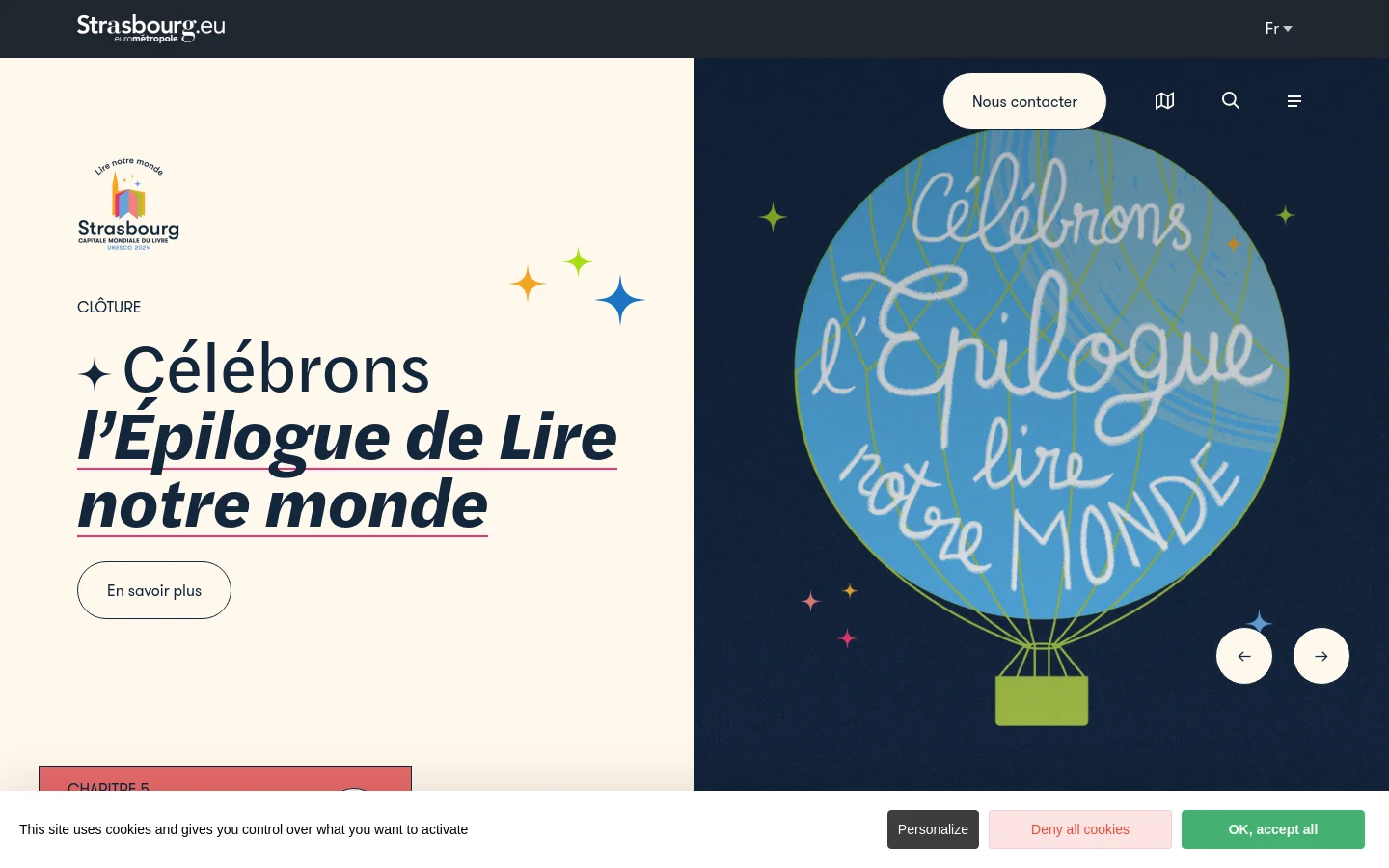 The desktop homepage features a split-screen hero section with a cream background on the left and a dark navy background on the right. On the left, large bold text reads 'Célébrons l’Épilogue de Lire notre monde' next to a 'En savoir plus' button, while the right side displays a large blue hot air balloon illustration with cursive text. The top navigation includes the Strasbourg logo, a language selector, and icons for search and menu.