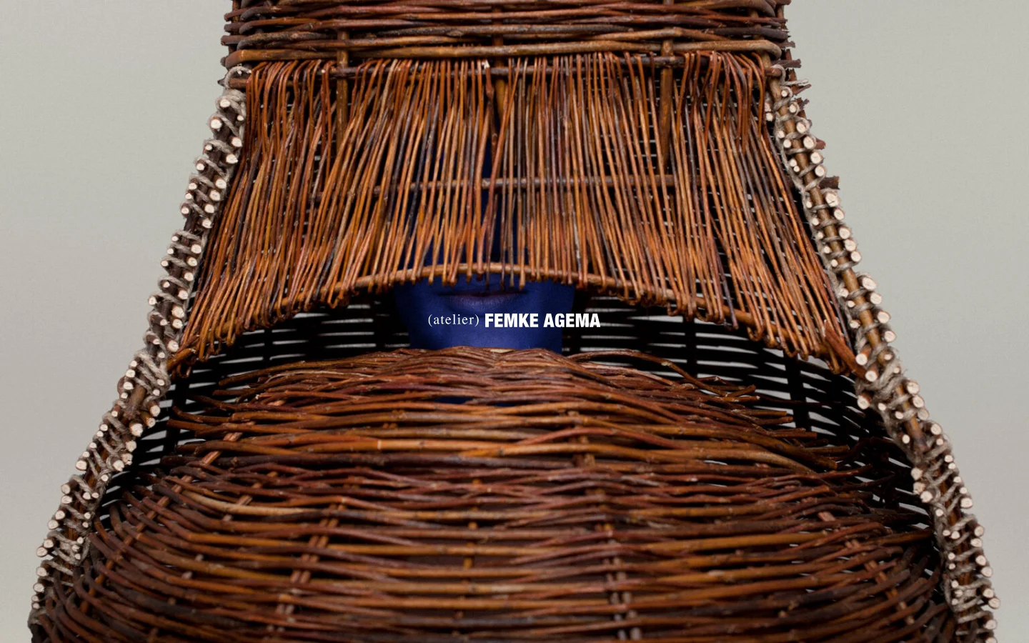 The desktop homepage features a minimalist design with a large, high-resolution hero image of a woven wicker sculptural object in warm brown tones. The text '(atelier) FEMKE AGEMA' is centered over the image, and a simple navigation layout includes 'Previous' and 'Next' links with a contact email at the bottom.