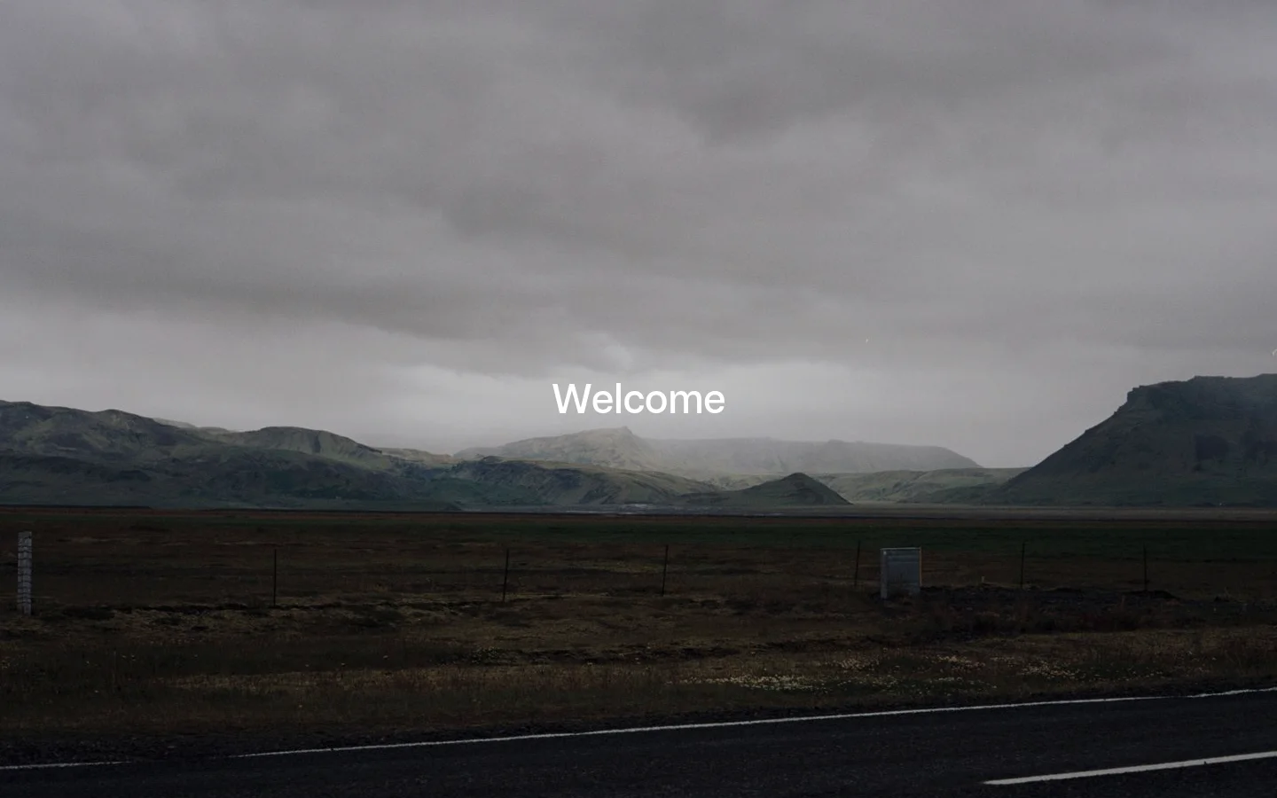 A minimalist desktop landing page featuring a large, cinematic background image of a moody, overcast landscape with mountains and a dark field under a cloudy sky. The word 'Welcome' is centered in large white text over the landscape, with the brand name 'Scandinavian Algorithms' and a 'Get in touch' email link appearing below in a clean, centered layout.