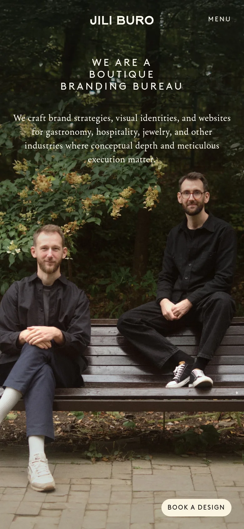 The mobile version presents a vertically stacked layout with the hero image occupying the background. The text is centered, featuring the brand name 'JILI BURO' and a 'MENU' button at the top, followed by the large headline and mission statement. The 'BOOK A DESIGN' call to action is positioned prominently at the bottom right.