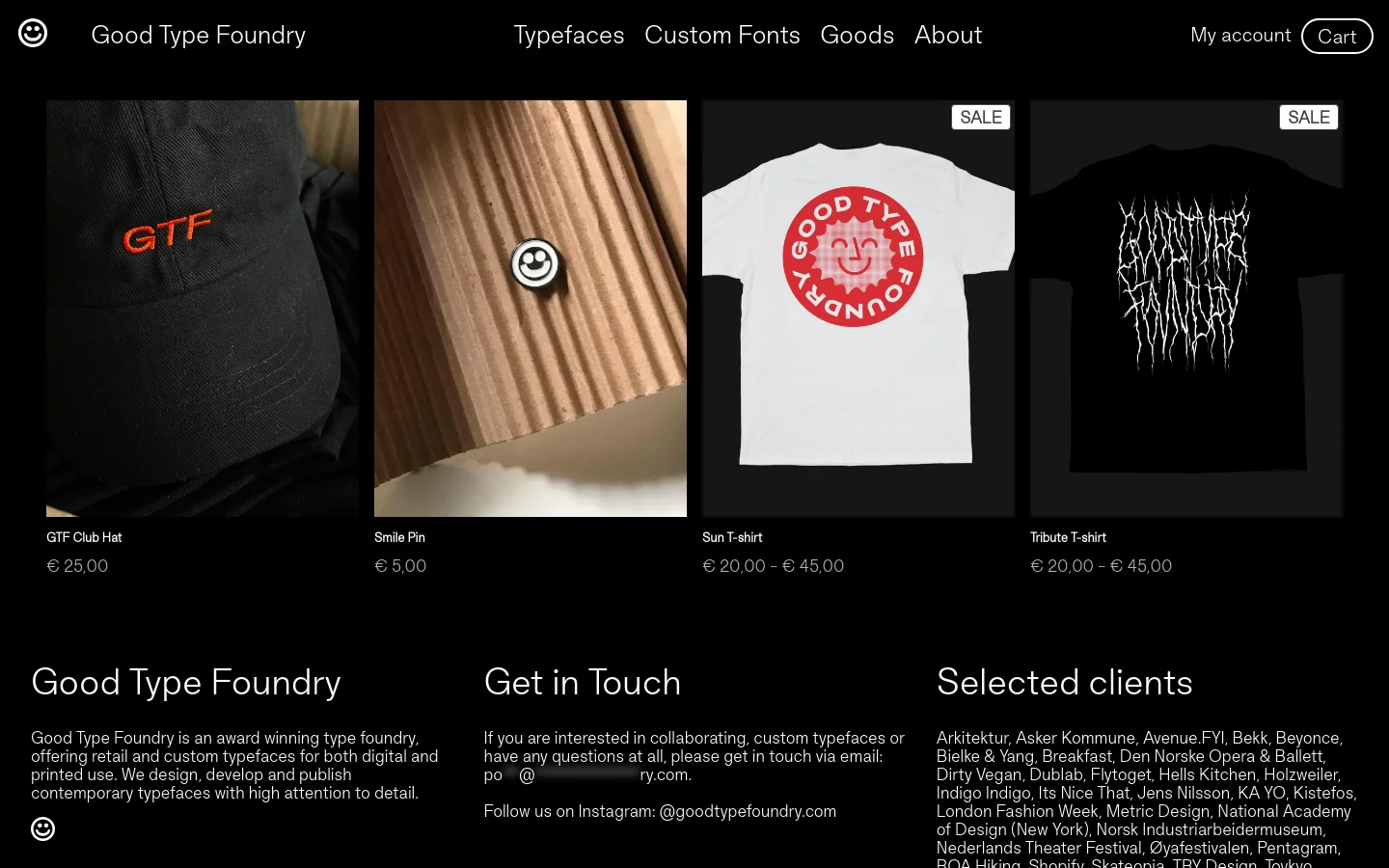 The desktop page features a minimalist black background with a grid of product images including a black hat, a smile pin, and two t-shirts. Each product image is followed by its name and price in white text, and the footer contains site information and contact details. The layout is clean and spacious, emphasizing the high-contrast product photography.