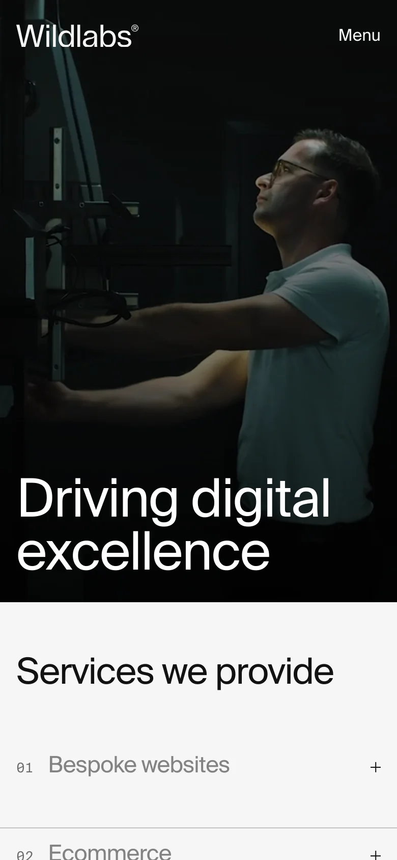 The mobile version displays a simplified layout with a dark hero image of a person working, featuring the headline 'Driving digital excellence'. The top navigation is replaced by a 'Menu' button next to the Wildlabs logo. The services section follows, presenting options like 'Bespoke websites' and 'Ecommerce' in a vertical list with expandable plus icons.
