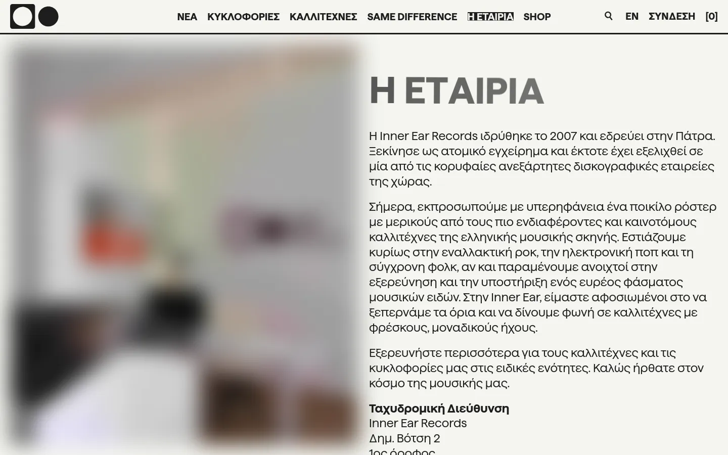 The desktop version features a clean white background with a top navigation menu containing links like 'NEA' and 'SHOP'. A large hero section displays a blurred office image on the left and a prominent 'H ΕΤΑΙΡΙΑ' headline with Greek text on the right. The layout is split horizontally between the visual element and the company description.