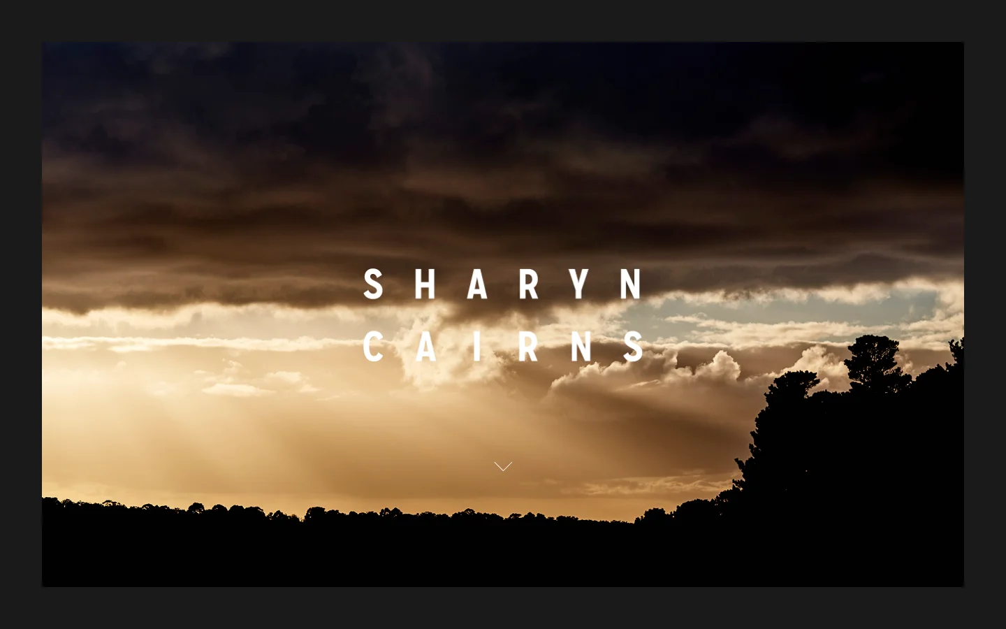 The desktop homepage features a full-width hero image of a dramatic sunset with golden light breaking through dark clouds over a silhouetted treeline. The name 'SHARYN CAIRNS' is centered in white, spaced-out capital letters, and a dark navigation bar sits at the top with a hamburger menu icon on the right.