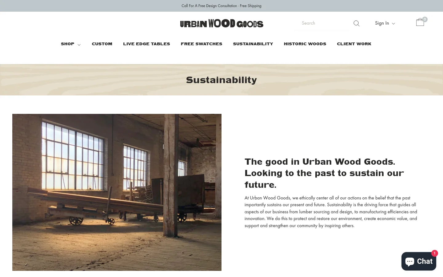 The desktop page features a clean white header with the Urban Wood Goods logo, navigation menu, and a search bar. A large hero banner with a light wood grain texture displays the title 'Sustainability' in bold black text. Below, a large photograph shows a sunlit, industrial workshop with large windows and heavy wooden machinery, positioned next to a headline and introductory text about the company's mission.