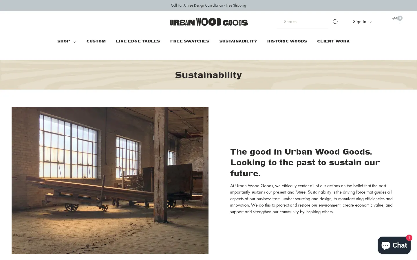 The desktop page features a clean white header with the Urban Wood Goods logo, navigation menu, and a search bar. A large hero banner with a light wood grain texture displays the title 'Sustainability' in bold black text. Below, a large photograph shows a sunlit, industrial workshop with large windows and heavy wooden machinery, positioned next to a headline and introductory text about the company's mission.