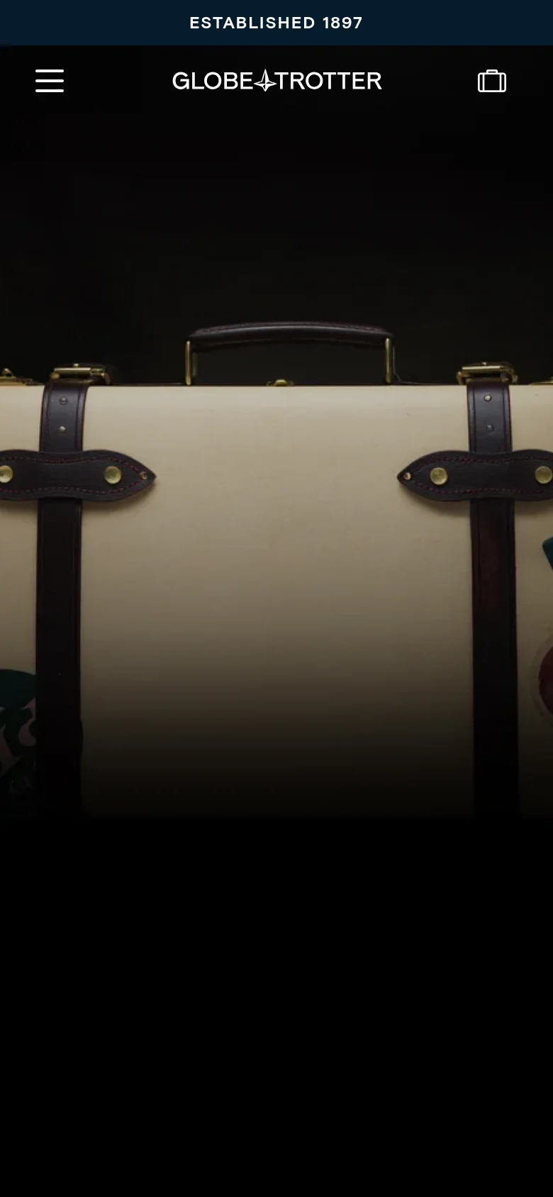 The mobile version simplifies the layout, replacing the horizontal navigation menu with a hamburger menu icon on the left and a shopping bag icon on the right. The Globe-Trotter logo remains centered at the top. The large hero image of the cream suitcase with leather details dominates the screen, maintaining the brand's luxury aesthetic.