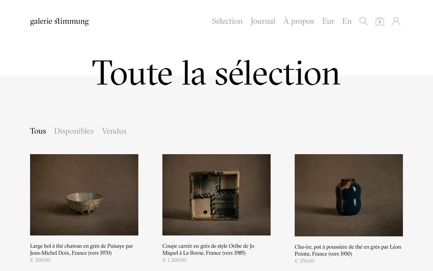 The desktop version of the 'Toute la sélection' page features a minimalist white layout with a centered headline and navigation links for 'Tous', 'Disponibles', and 'Vendus'. A grid of ceramic artworks is displayed, each with a high-quality photograph, a descriptive title in French, and a price. The header includes the gallery name, main menu links, language/currency selectors, a search icon, a shopping bag, and a user profile icon.