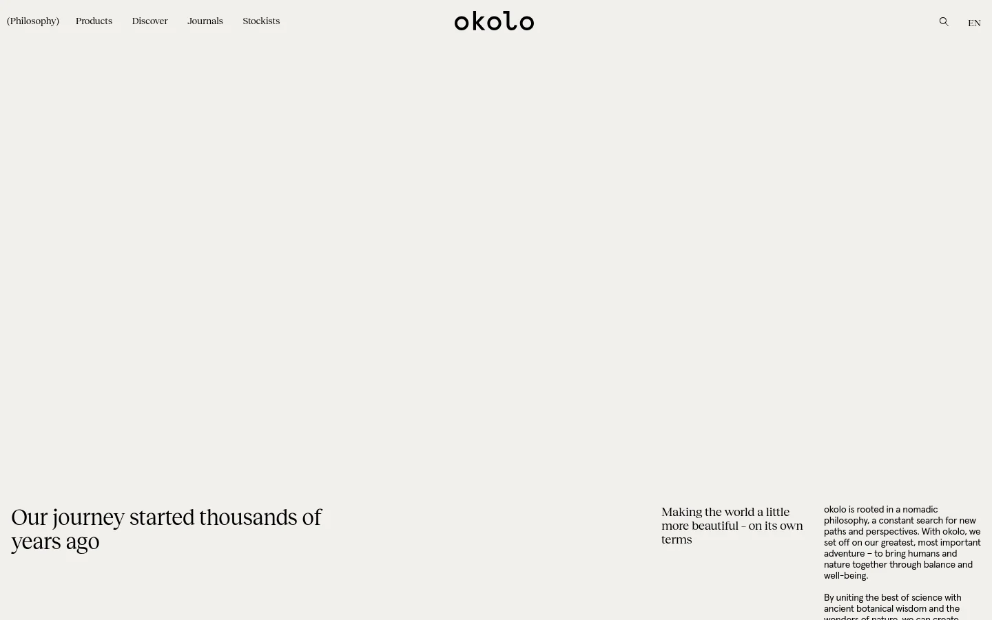 The desktop page features a minimalist design with a white background and black serif typography. A large hero section includes a blurred, abstract landscape image in earthy tones, accompanied by the headlines 'Our journey started thousands of years ago' and 'Making the world a little more beautiful - on its own terms.' The navigation menu is positioned at the top with links for Products, Discover, Journals, and Stockists.