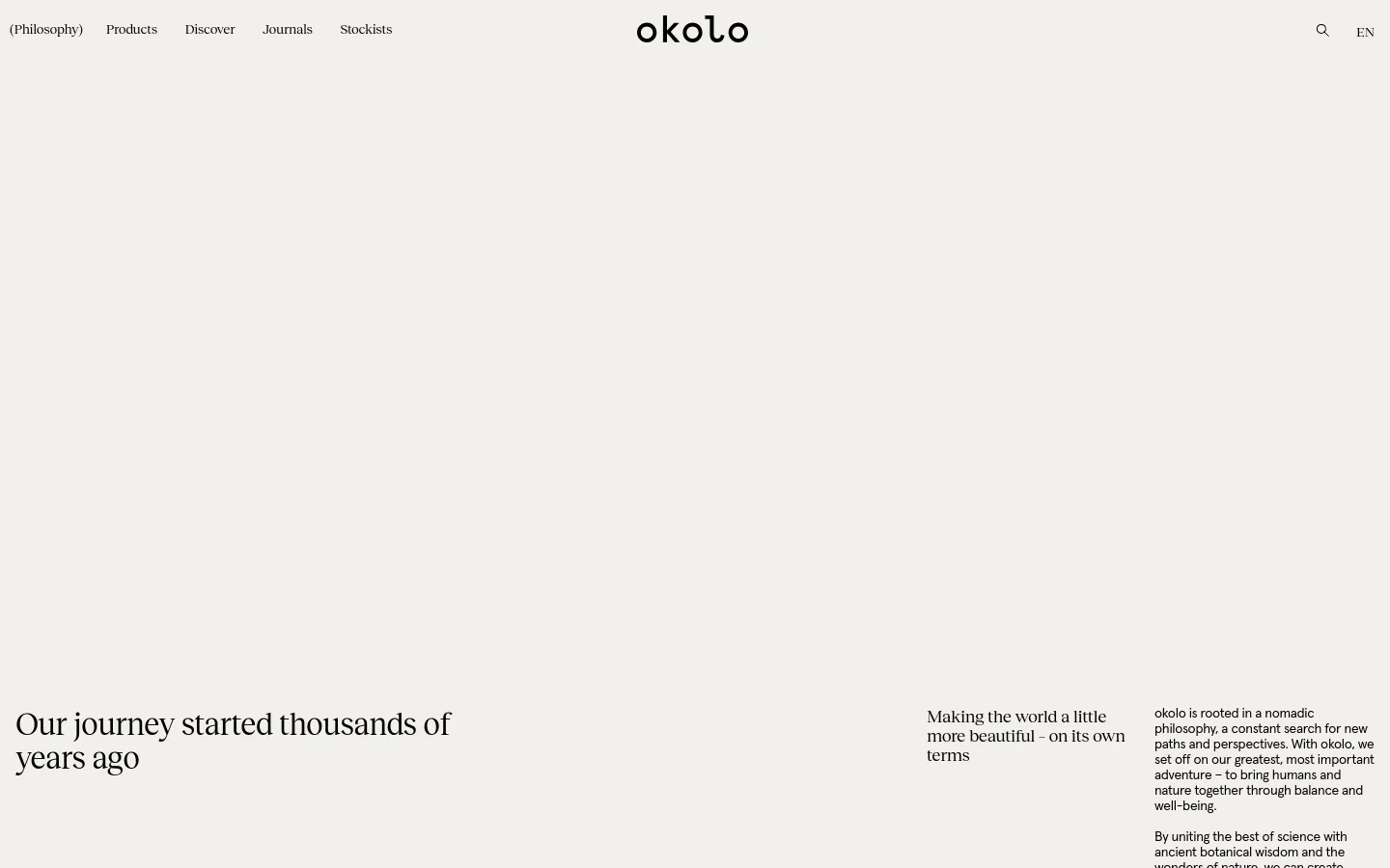 The desktop page features a minimalist design with a white background and black serif typography. A large hero section includes a blurred, abstract landscape image in earthy tones, accompanied by the headlines 'Our journey started thousands of years ago' and 'Making the world a little more beautiful - on its own terms.' The navigation menu is positioned at the top with links for Products, Discover, Journals, and Stockists.