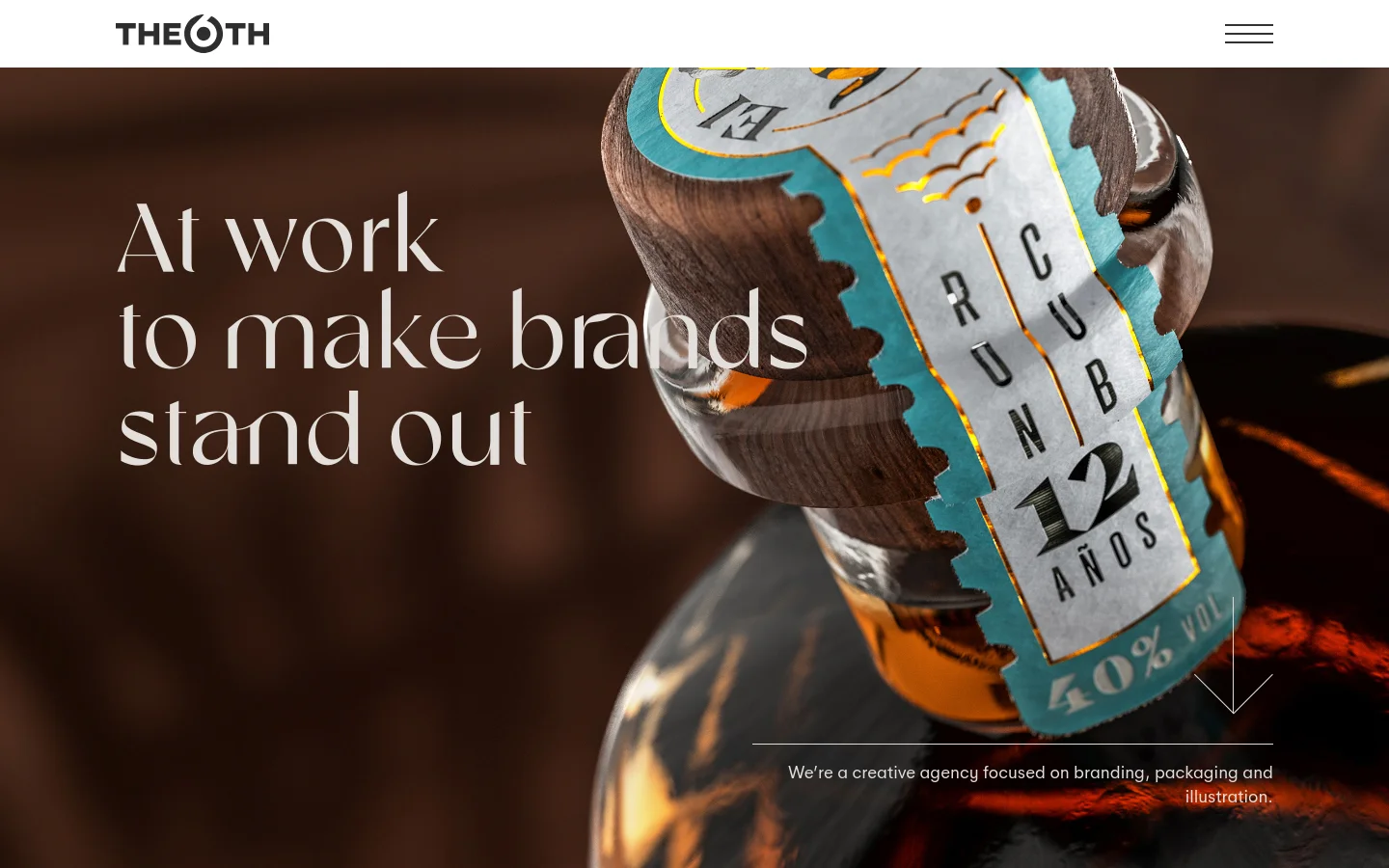 The desktop homepage for The 6th creative agency features a large hero image of a detailed product bottle with a wooden cap and decorative label. A bold serif headline reads 'At work to make brands stand out' against a dark brown background, with a brief agency description and a downward arrow at the bottom right.