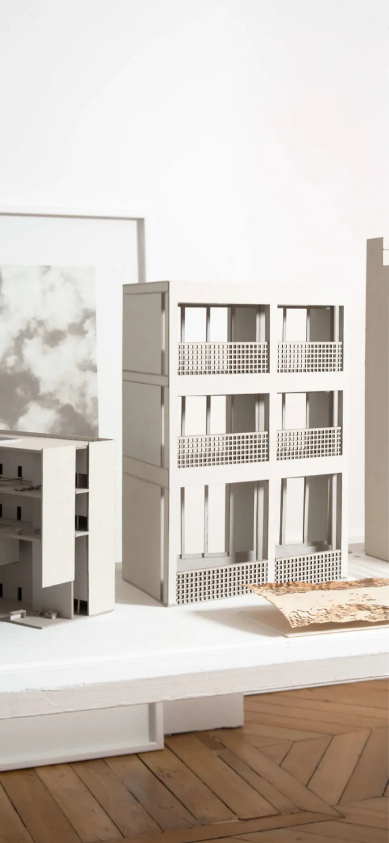 The mobile version maintains the minimalist aesthetic but presents a vertically oriented, cropped version of the architectural model hero image. The navigation links are stacked or condensed to fit the narrow screen, and the overall layout prioritizes the large-scale imagery over the horizontal menu structure seen on desktop.