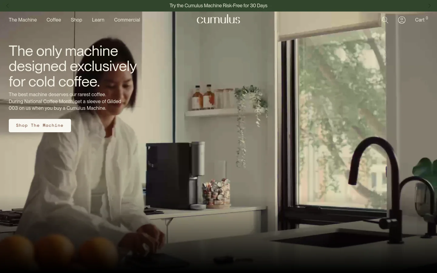 Desktop homepage featuring a large hero image of a person in a modern kitchen with a Cumulus coffee machine. A headline reads 'The only machine designed exclusively for cold coffee' next to a 'Shop The Machine' button. Below the hero section, a row of media logos including Entrepreneur, Bon Appétit, and Bloomberg is displayed against a clean, light background.