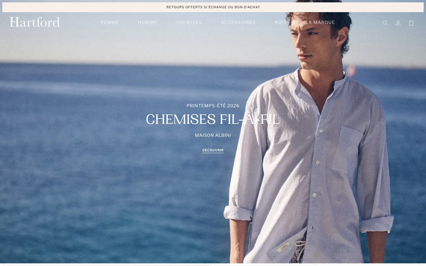 The desktop homepage features a large hero image of a man in a light blue shirt against a coastal sea background, with the headline 'CHEMISES FIL-À-FIL' and a 'DÉCOUVRIR' call to action. Below, the layout transitions into a grid of product images and promotional banners for men's and women's collections, using a clean white and neutral color palette. The navigation menu is spread horizontally across the top with links for Femme, Homme, Chemises, Accessoires, Kids, and La Marque.