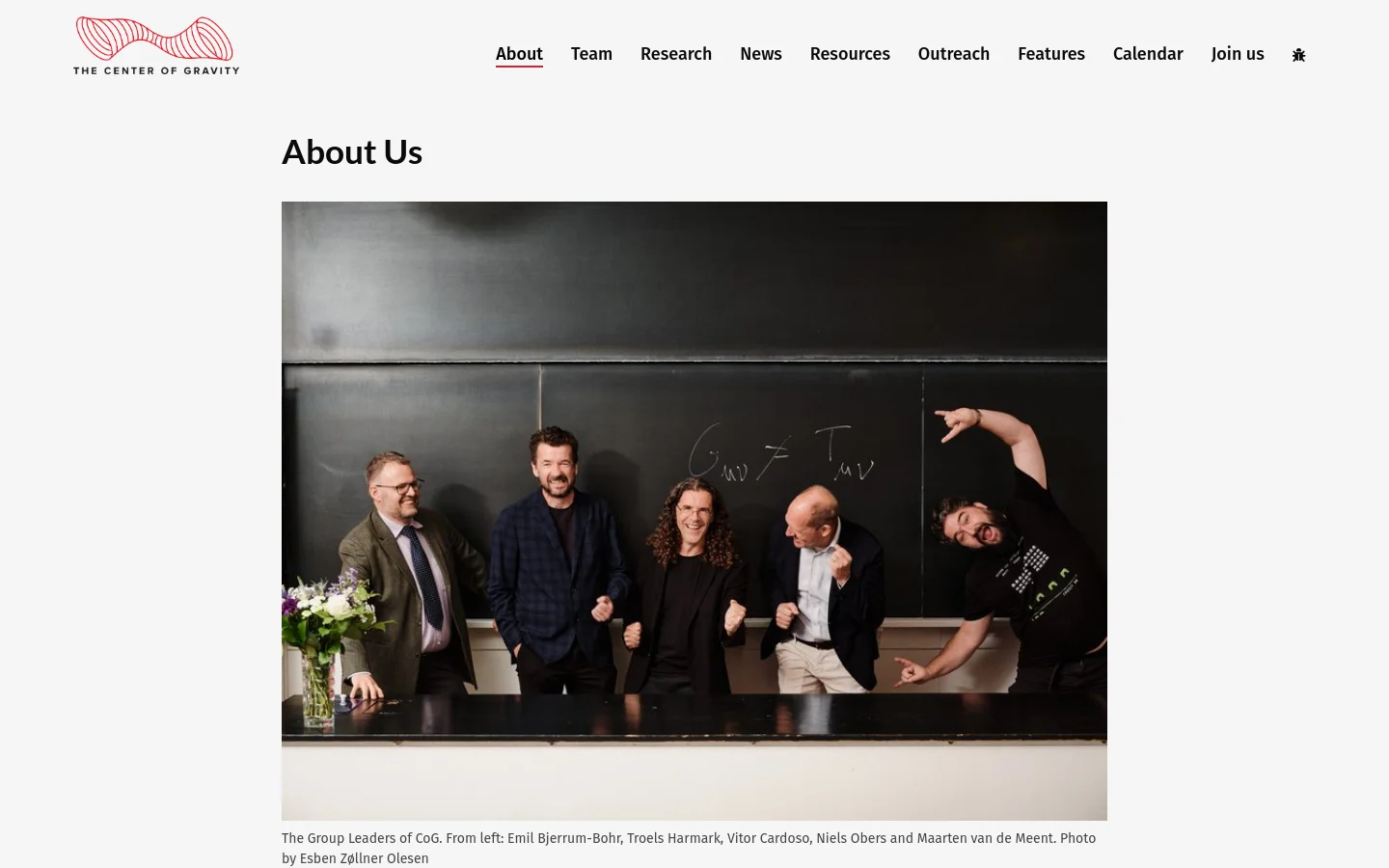 The About Us page features a clean white background with a navigation menu at the top right. A large hero image shows five group leaders posing playfully in front of a chalkboard, followed by a large 'About Us' heading and several paragraphs of text describing the Center of Gravity.