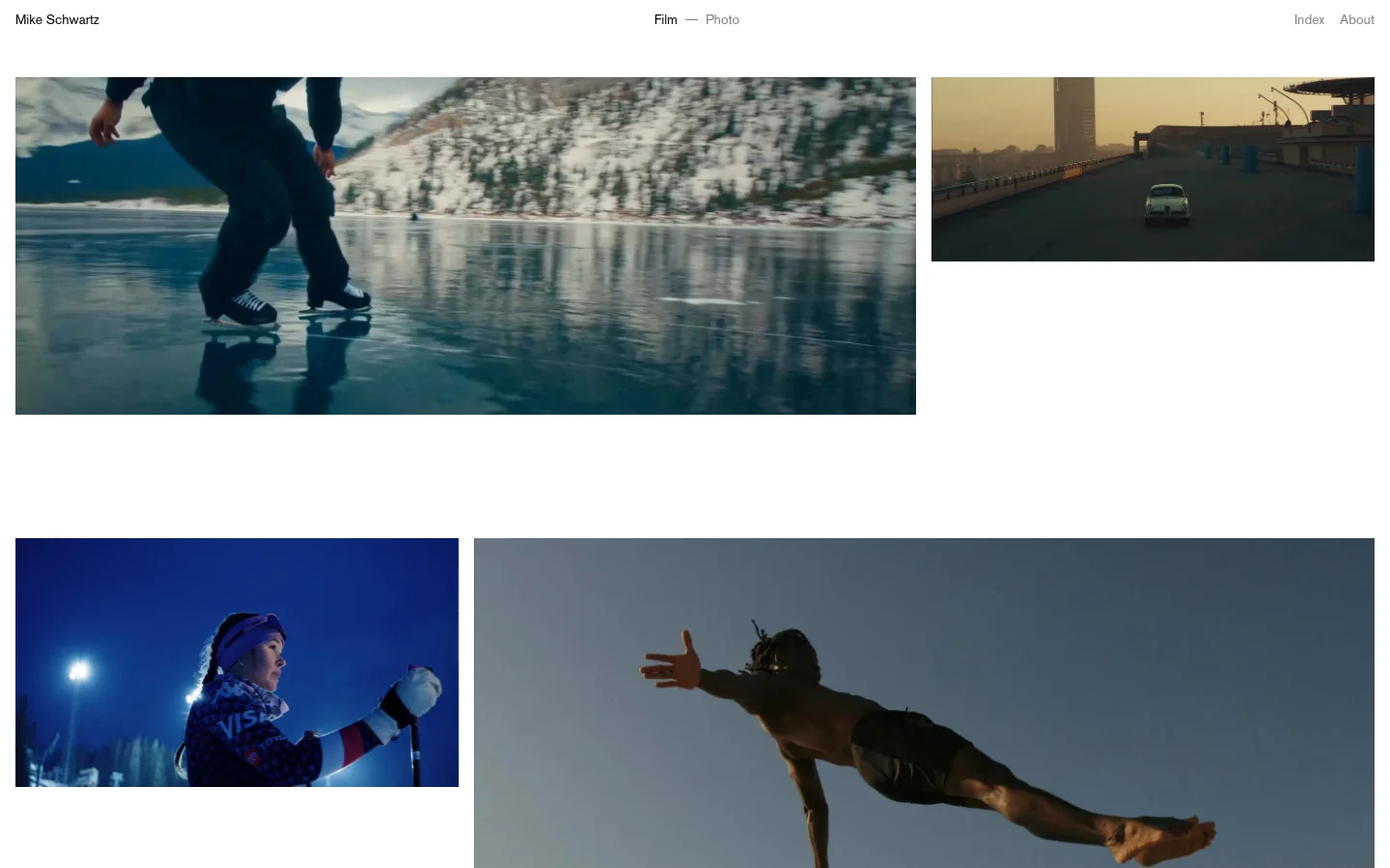 The desktop homepage features a minimalist design with a white background and a navigation menu at the top containing 'Mike Schwartz', 'Film', 'Photo', 'Index', and 'About'. The main content consists of a large vertical grid of cinematic video thumbnails showcasing various film projects, each accompanied by a title and duration. The layout is spacious, using high-quality imagery to create a professional portfolio feel.