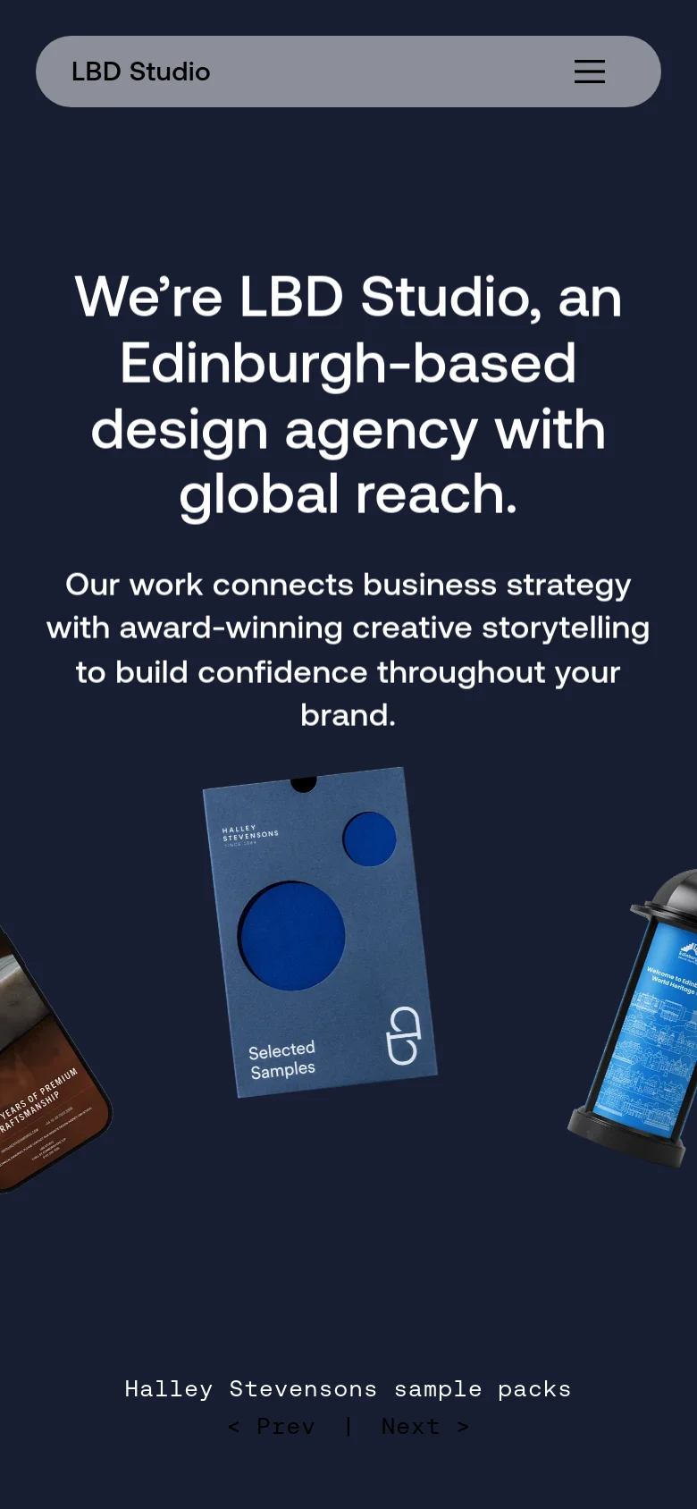 The mobile version uses a dark navy background with the same large white headline and subtext centered vertically. The product imagery, including the blue folder and black container, is rearranged and partially cropped to fit the narrow screen. The top navigation is replaced by a simplified light grey bar containing the studio name and a hamburger menu icon.