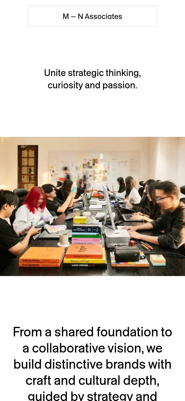 The mobile version maintains the minimalist white background and centered typography but scales the content vertically. The hero image of the design team is narrower to fit the portrait screen, and the text blocks are stacked for easier scrolling on a small device.