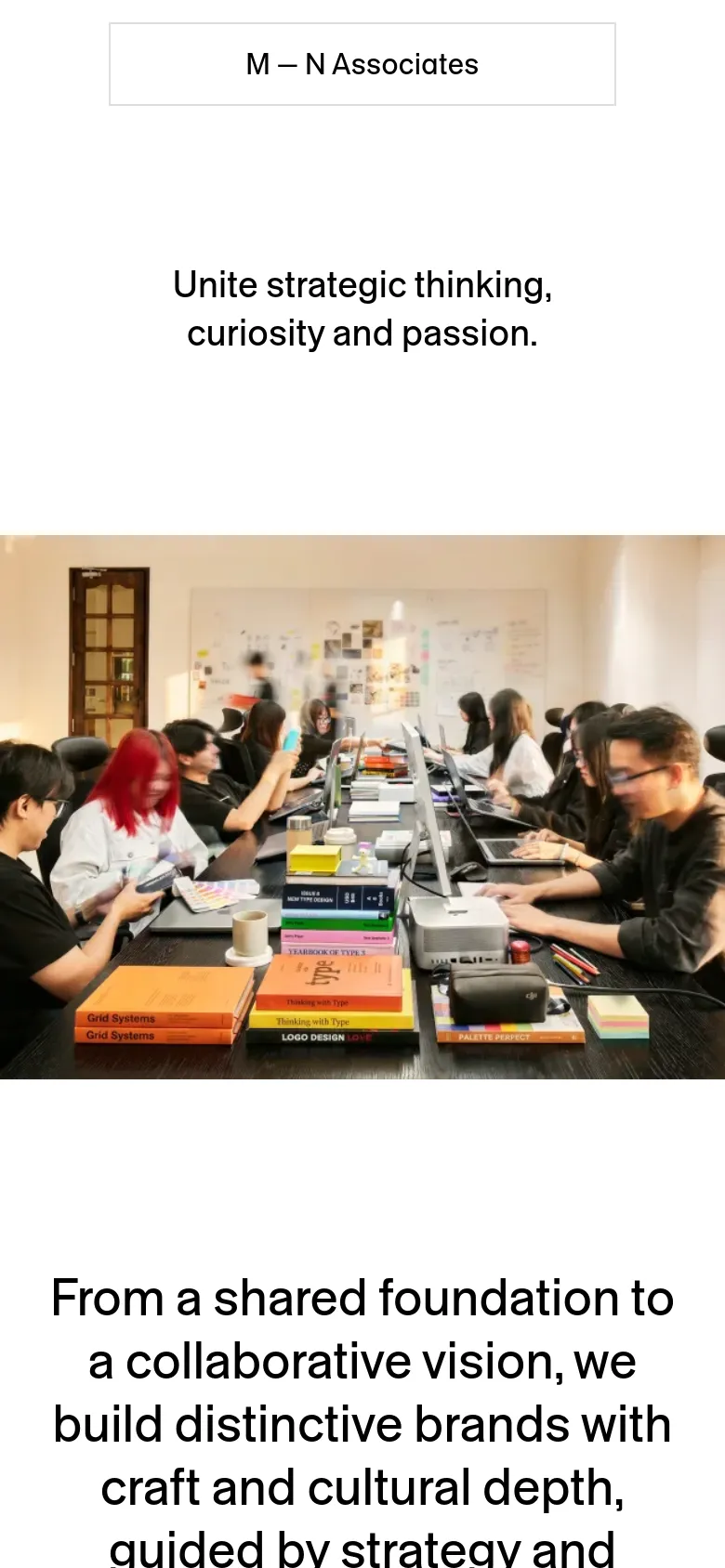 The mobile version maintains the minimalist white background and centered typography but scales the content vertically. The hero image of the design team is narrower to fit the portrait screen, and the text blocks are stacked for easier scrolling on a small device.