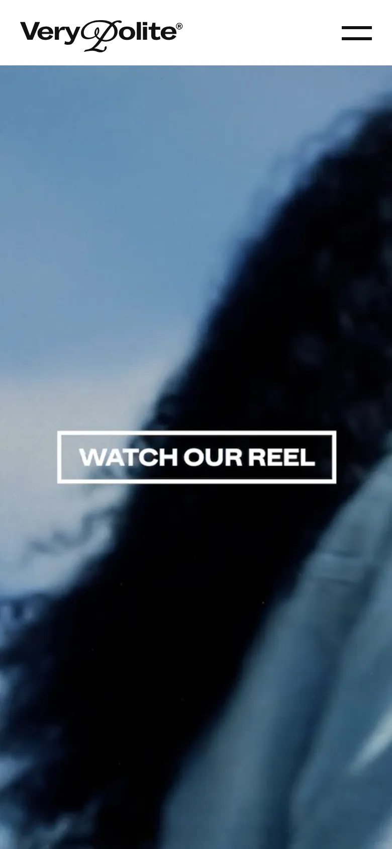 The mobile version maintains the minimalist white header with the logo and a larger hamburger menu icon. The hero section shows a zoomed-in, vertical crop of the cinematic black-and-white imagery with the 'WATCH OUR REEL' button centered prominently over the visual.