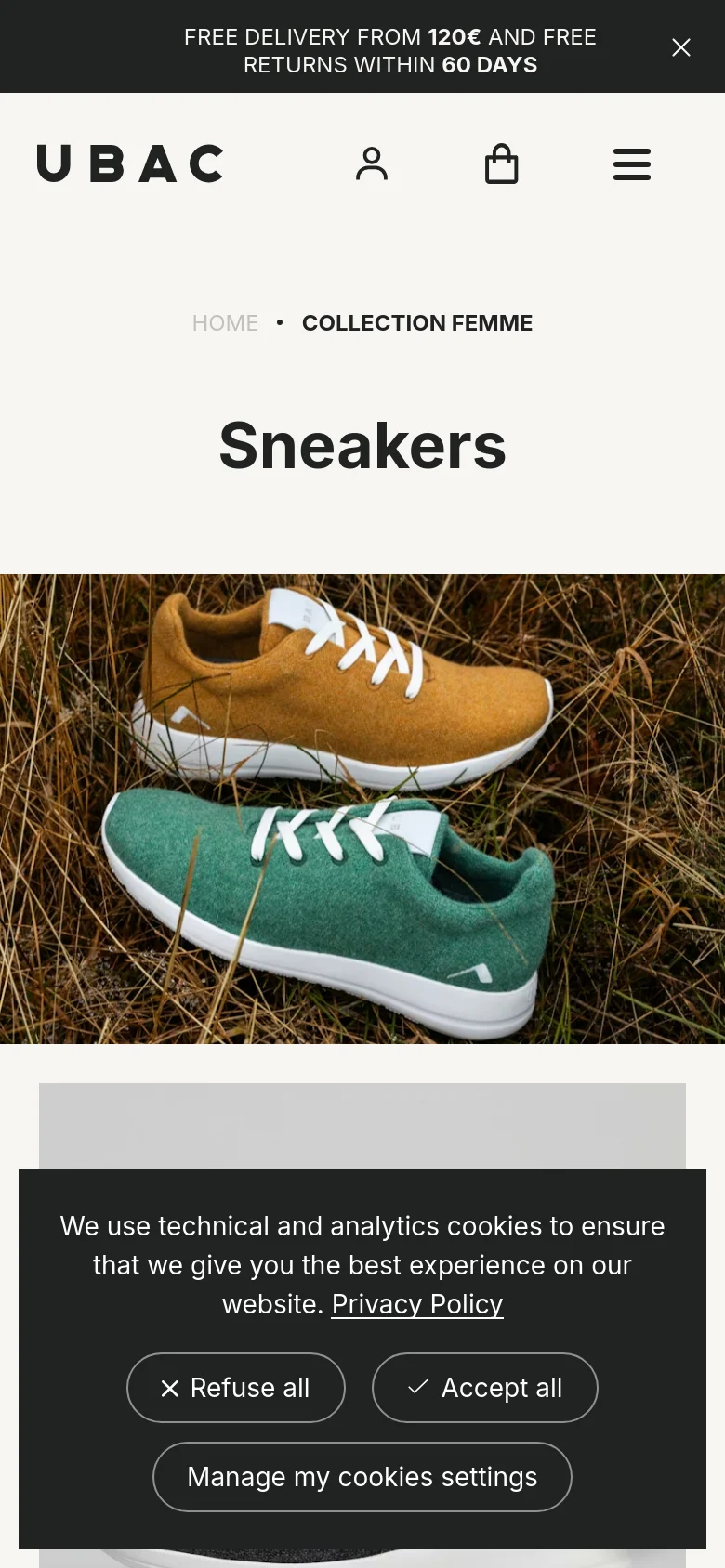 Mobile view of the collection page with a simplified vertical layout. The headline 'Sneakers' is centered above a large hero image of two sneakers resting in tall grass. A hamburger menu, user icon, and shopping bag icon are located in the header, and a cookie consent banner appears at the bottom.