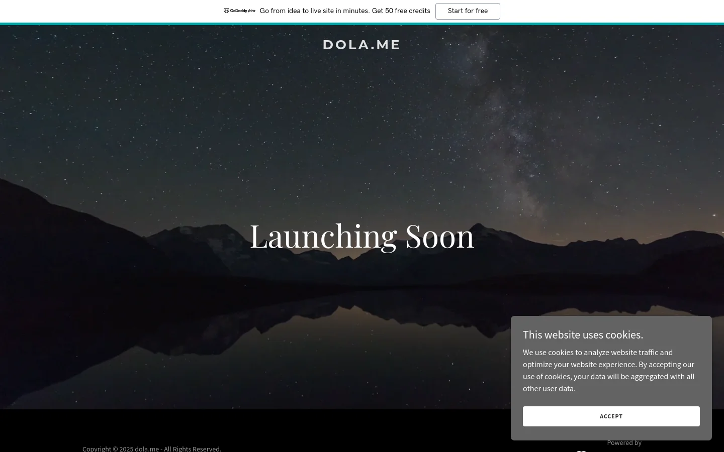 The desktop homepage features a dark, cinematic hero image of a starry night sky over mountains reflected in a calm lake. Centered in large white serif typography is the headline 'Launching Soon', with the 'DOLA.ME' logo at the top center. A thin teal banner at the top promotes GoDaddy Airo, and a cookie consent pop-up appears in the bottom right corner.