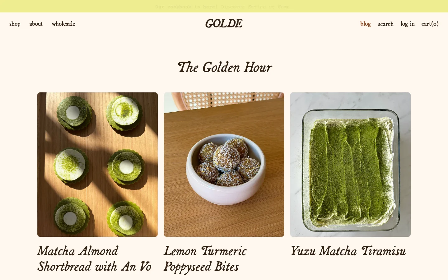 The desktop version of The Golden Hour blog features a cream-colored background with a minimalist navigation bar at the top. Below the 'The Golden Hour' headline, a grid of large, high-quality food photography displays blog posts, including Matcha Almond Shortbread and Lemon Turmeric Poppyseed Bites.