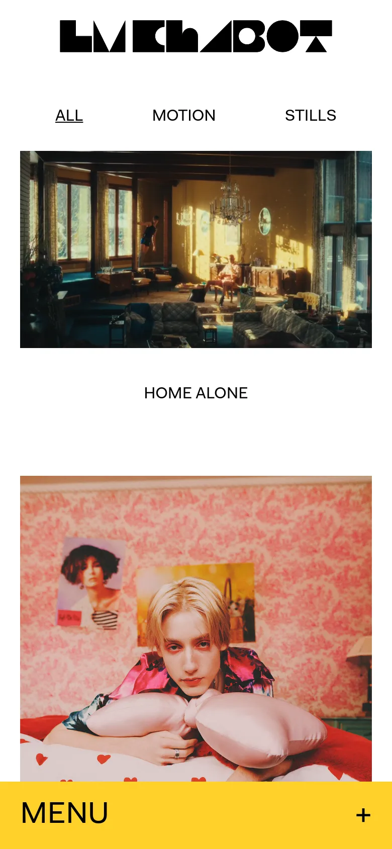 The mobile version presents a simplified vertical layout with the black logo and navigation links at the top. The photography projects are stacked vertically, showing large, full-width images such as an interior room and a person on a pink bed. A prominent yellow bar at the bottom contains a 'MENU' button with a plus icon.