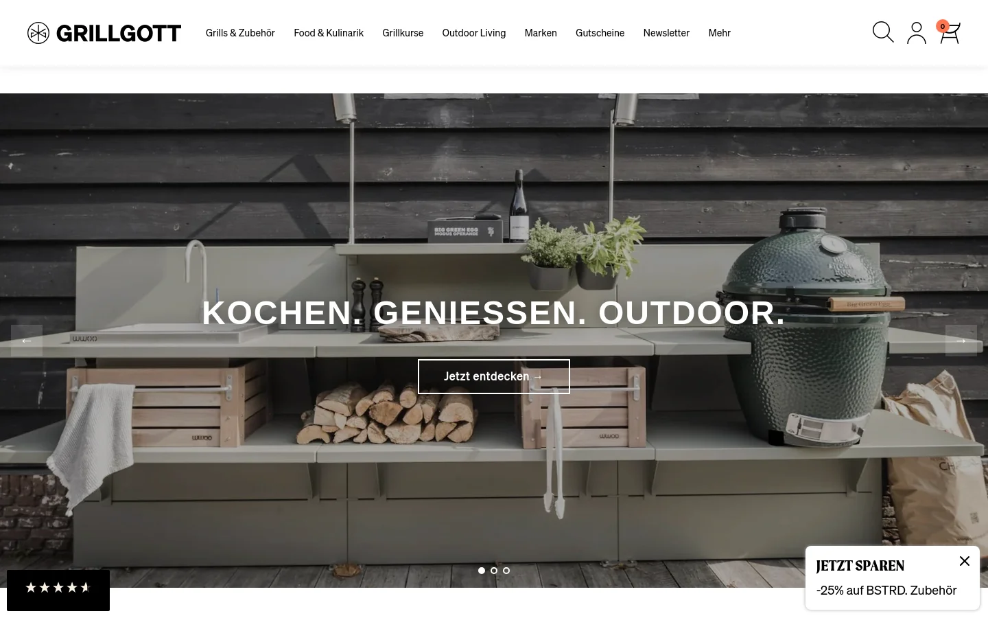 The desktop homepage features a wide hero image of a modern, sage-green outdoor kitchen module set against dark wood siding, featuring a Big Green Egg grill and wooden storage crates. Centered white text reads 'KOCHEN. GENIESSEN. OUTDOOR.' above a 'Jetzt entdecken' call-to-action button. The navigation bar at the top includes the Grillgott logo, various product categories, a search icon, and a shopping cart.