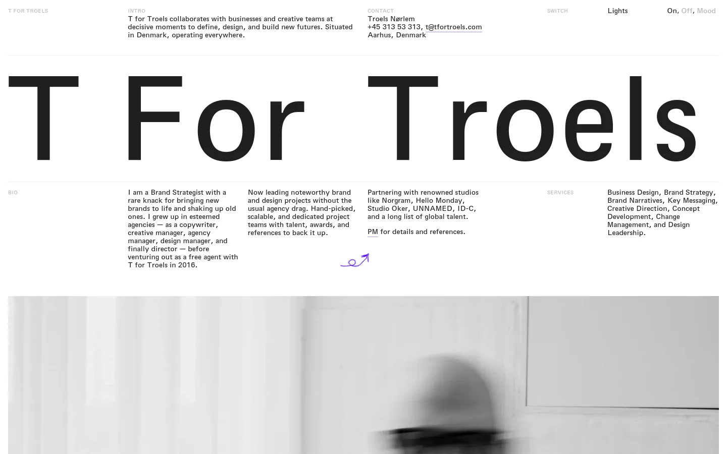 The desktop homepage features a minimalist, high-contrast black and white design with large, bold typography. The brand name 'T For Troels' dominates the center, surrounded by sections for Bio, Services, and Principles arranged in a clean, spacious grid layout. A large, blurred black and white photographic element is visible at the bottom of the page.