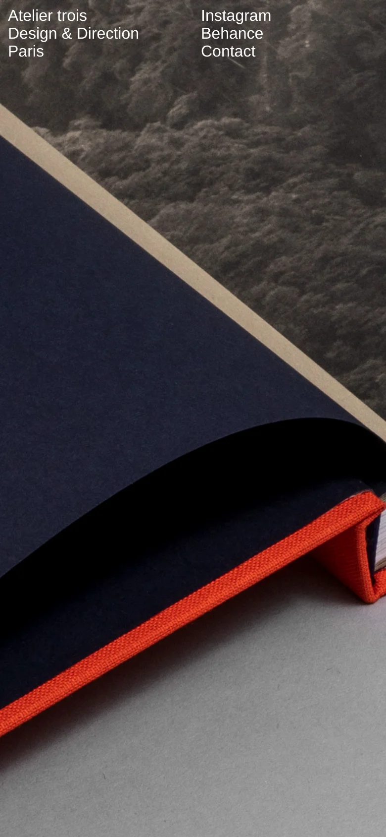 The mobile version maintains the same minimalist aesthetic and high-angle book photography but uses a vertically oriented crop. The text elements are repositioned to fit the narrower screen, keeping the brand information and navigation links visible at the top of the frame.